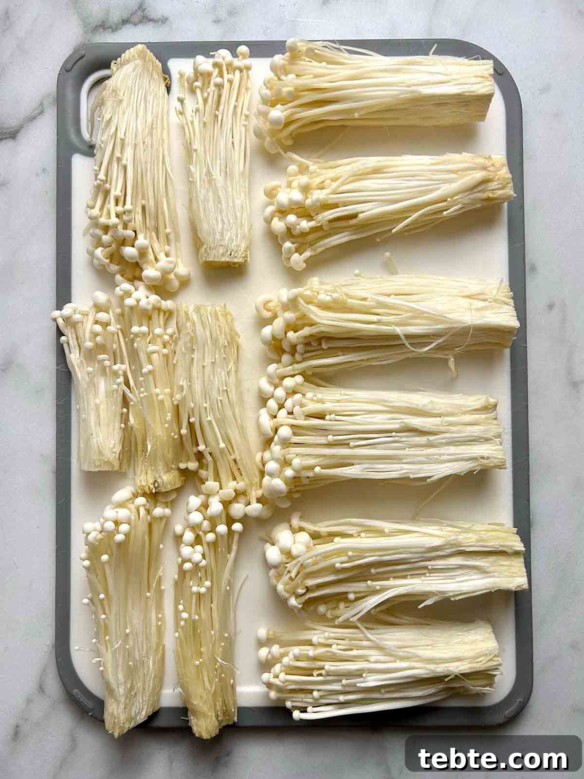 separated enoki strands on cutting board