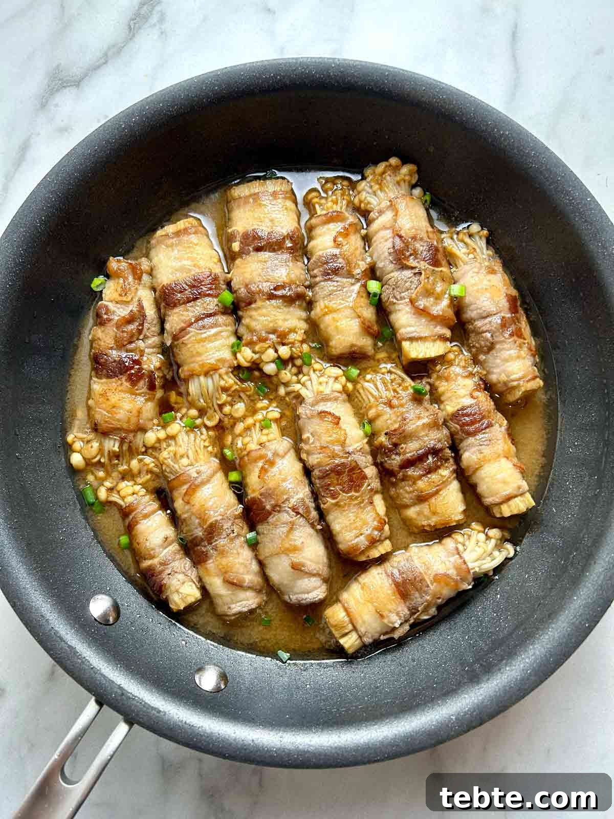 simmering enoki beef rolls in pan