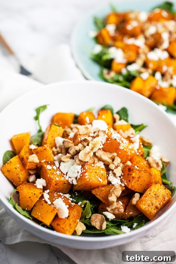 41 Fresh Fall Salad Recipes to Try This Season 16 A white bowl filled with greens and topped with roasted squash, walnuts, and feta cheese.