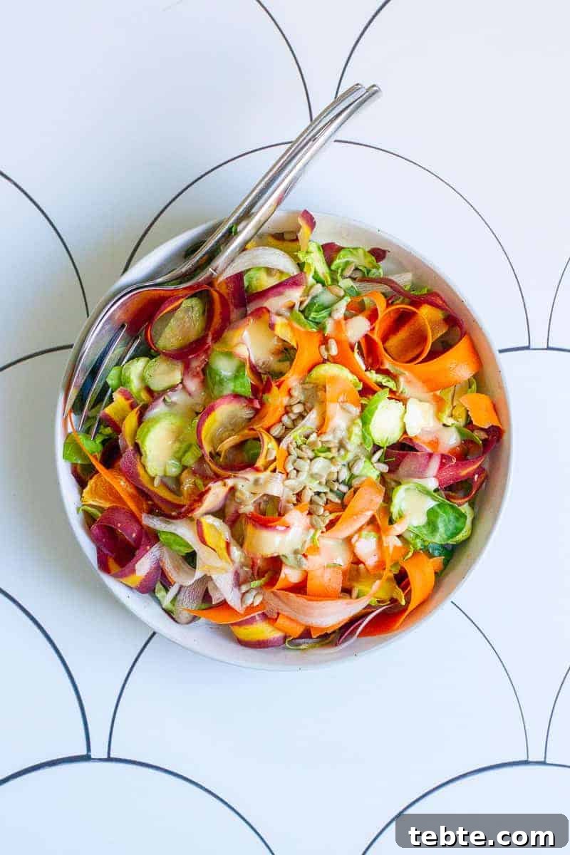41 Fresh Fall Salad Recipes to Try This Season 31 A white bowl sitting on a geometric pattern, full of sliced brussels sprouts, thin ribbons of rainbow carrots and sprinkled with sunflower seeds. A fork is tucked in on top of the salad.