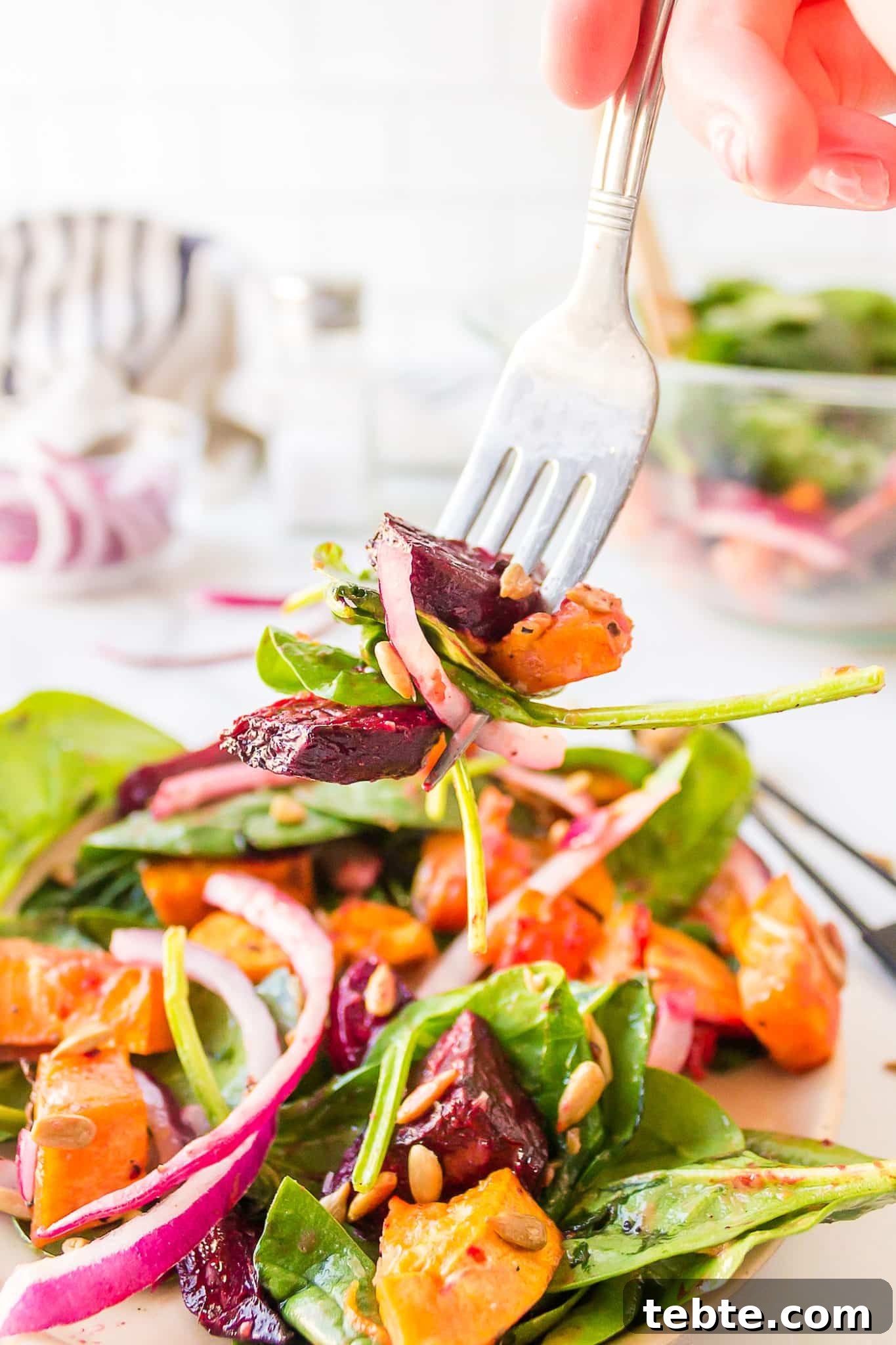 41 Fresh Fall Salad Recipes to Try This Season 35 A hand with a forkful of beets, sweet potatoes, greens, a slice of red onion and sunflower seeds, held over a plate of the salad. A bowl of salad and the extra ingredients are in the background with a salt shaker.