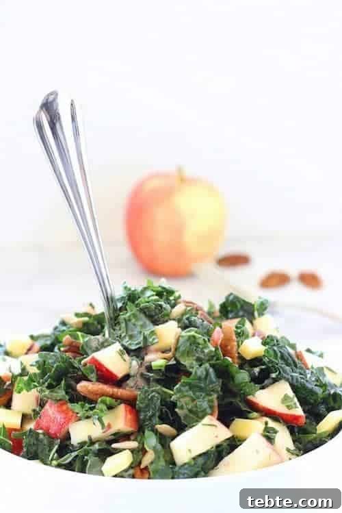 41 Fresh Fall Salad Recipes to Try This Season 40 A white bowl filled with kale, diced apples, pecans, and sunflower seeds. There is a fork in the middle of the salad, with a red apple and extra pecans sprinkled in the background.