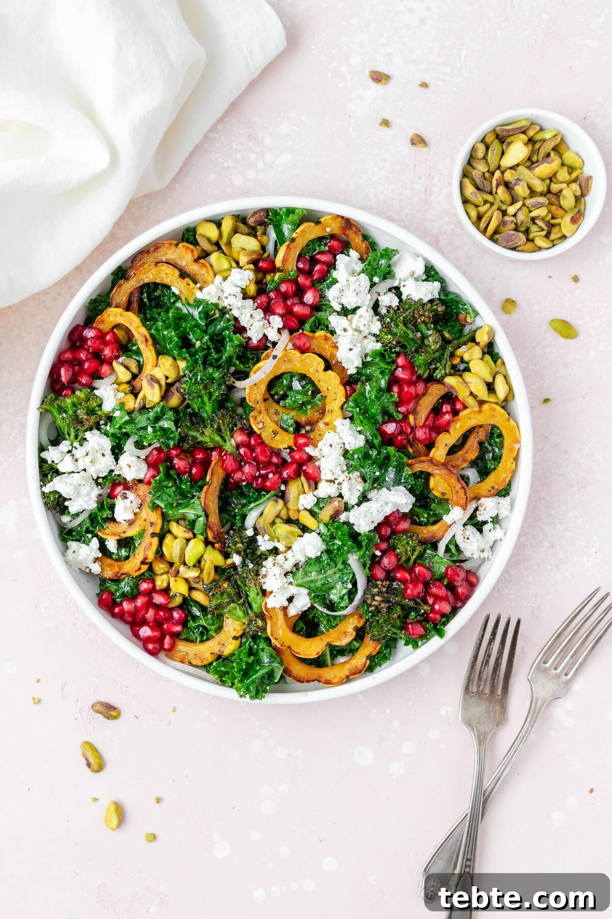 41 Fresh Fall Salad Recipes to Try This Season 10 A white bowl filled with leafy green kale, slices of orange squash, pistachios, pomegranate seeds and chunks of goat cheese. A bowl of pistachios sits above the salad with a set of forks and a white napkin on each side of the bowl.