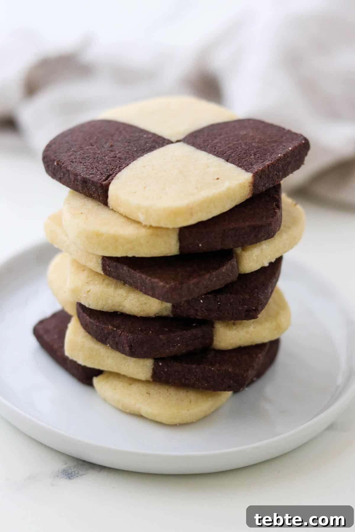 Stack of checkerboard cookies on a plate.