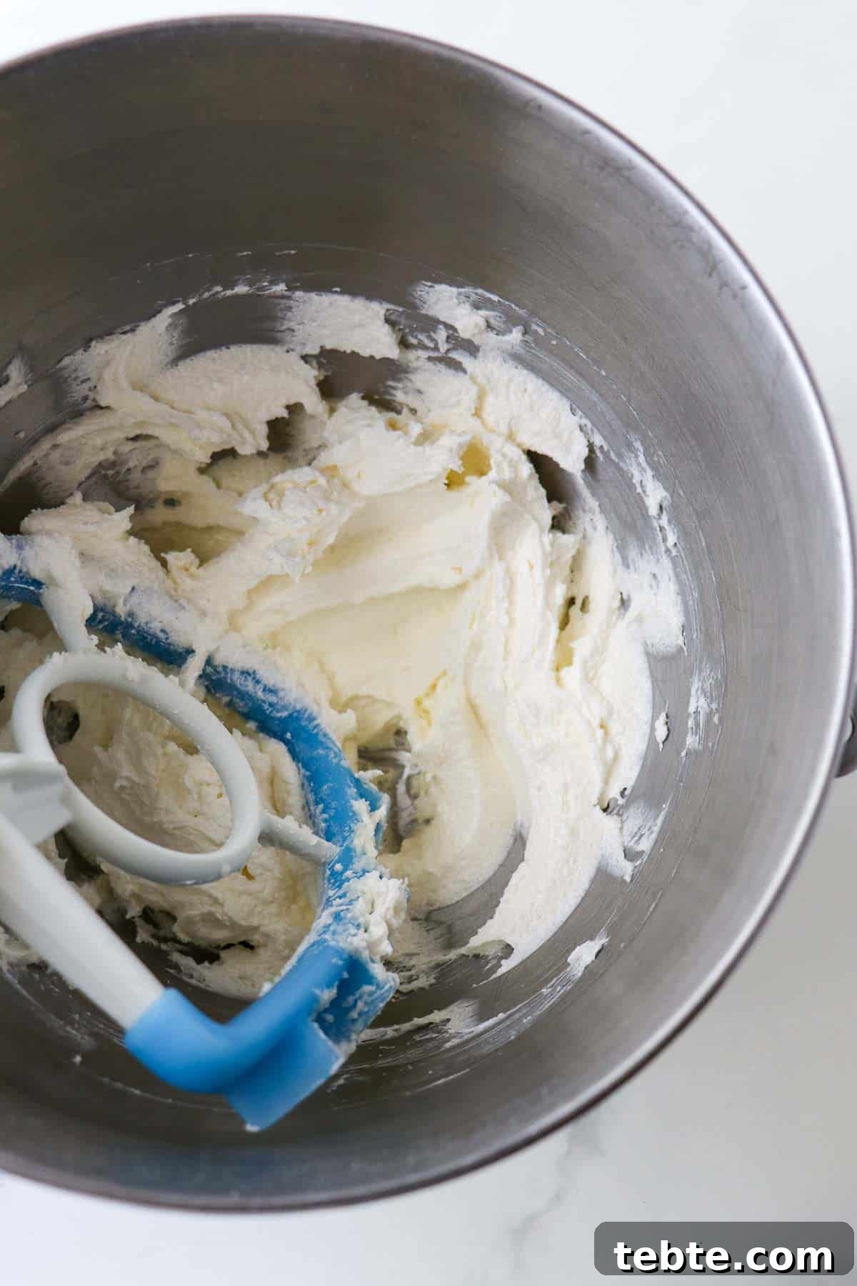 Butter and sugar creamed together in a metal bowl with a paddle attachment.