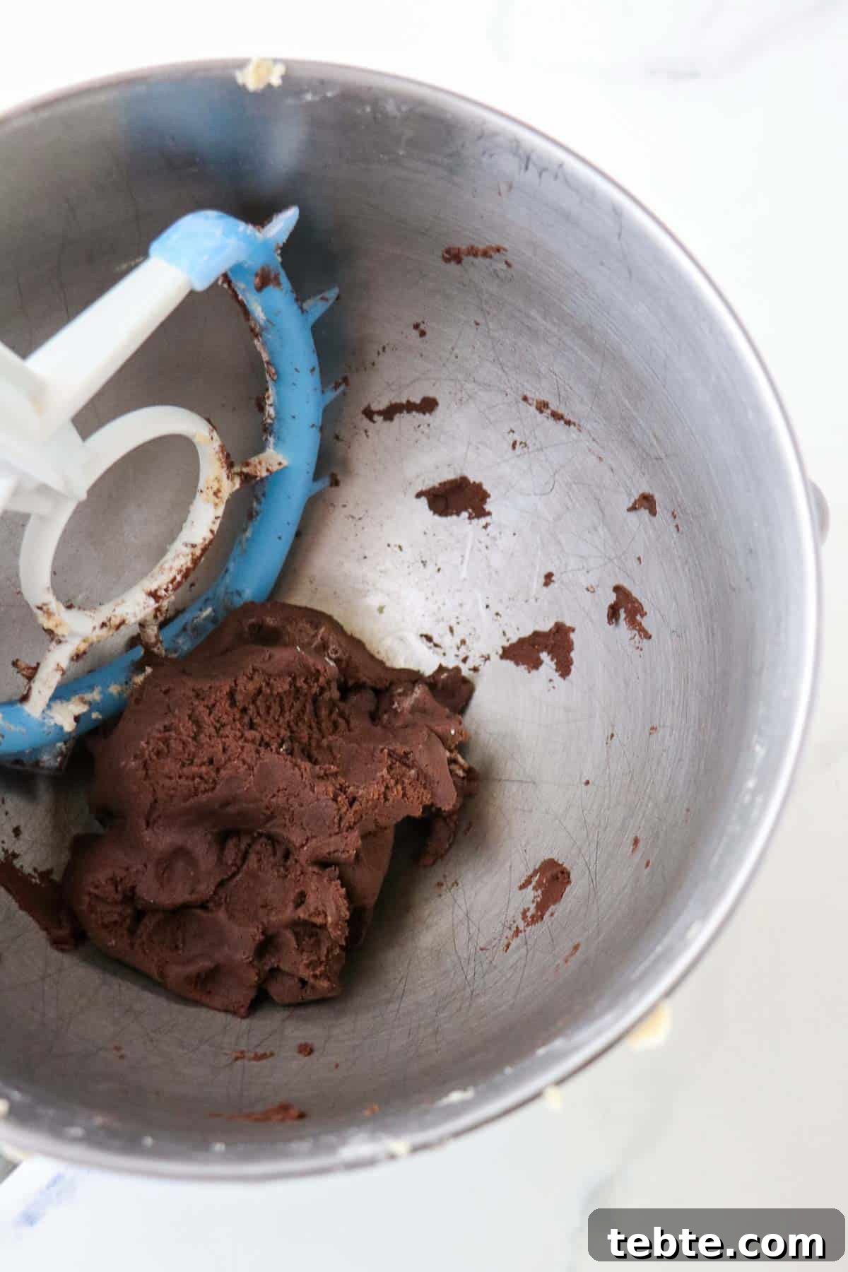 Chocolate cookie dough in a bowl with a paddle attachment.