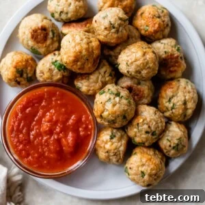 Crispy Baked Chicken Meatballs with Garlic Herb Sauce 8 a plate filled with meatballs and a small bowl of marinara sauce
