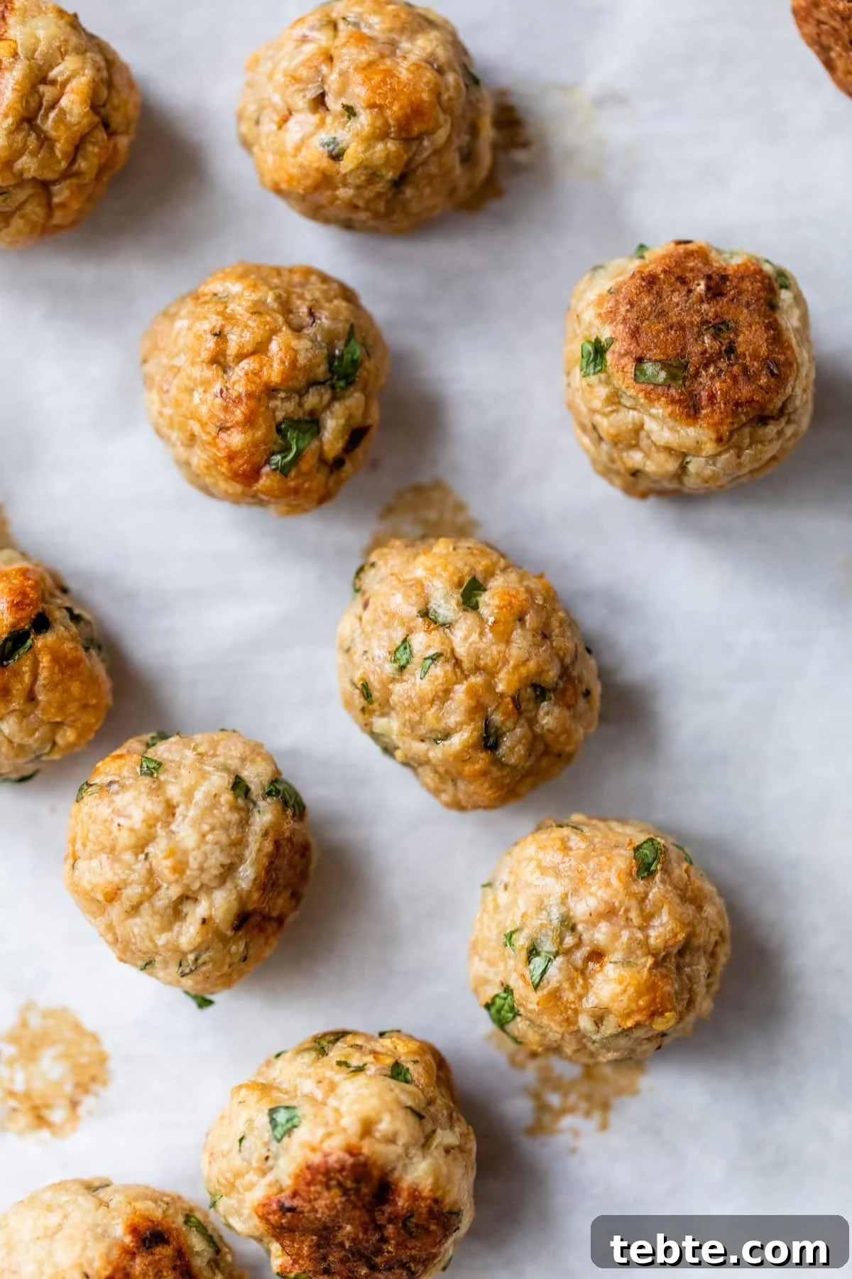 Crispy Baked Chicken Meatballs with Garlic Herb Sauce 4 baked meatballs on parchment paper