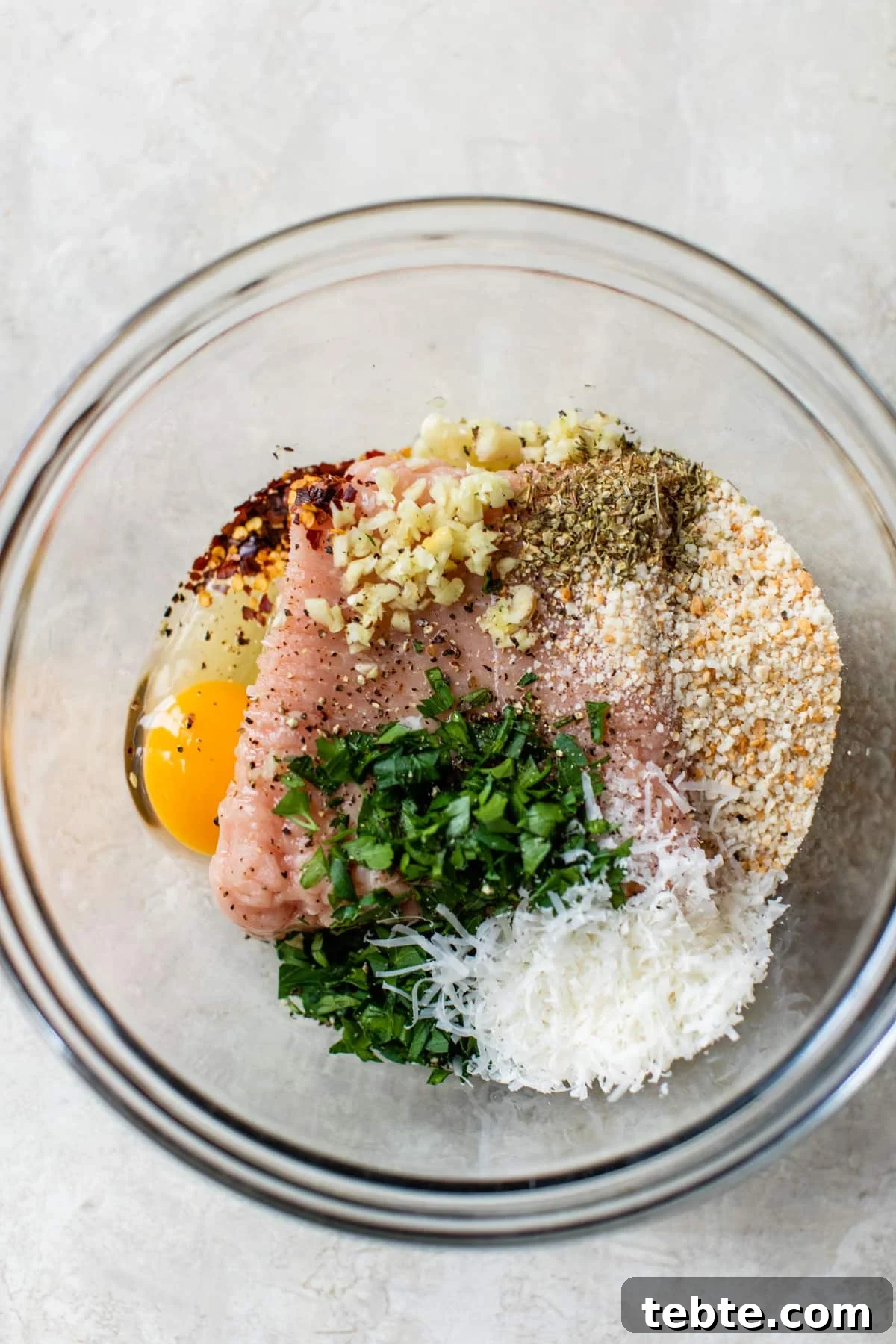 Crispy Baked Chicken Meatballs with Garlic Herb Sauce 5 ground chicken, egg, parsley, breadcrumbs, cheese, and garlic in a glass bowl