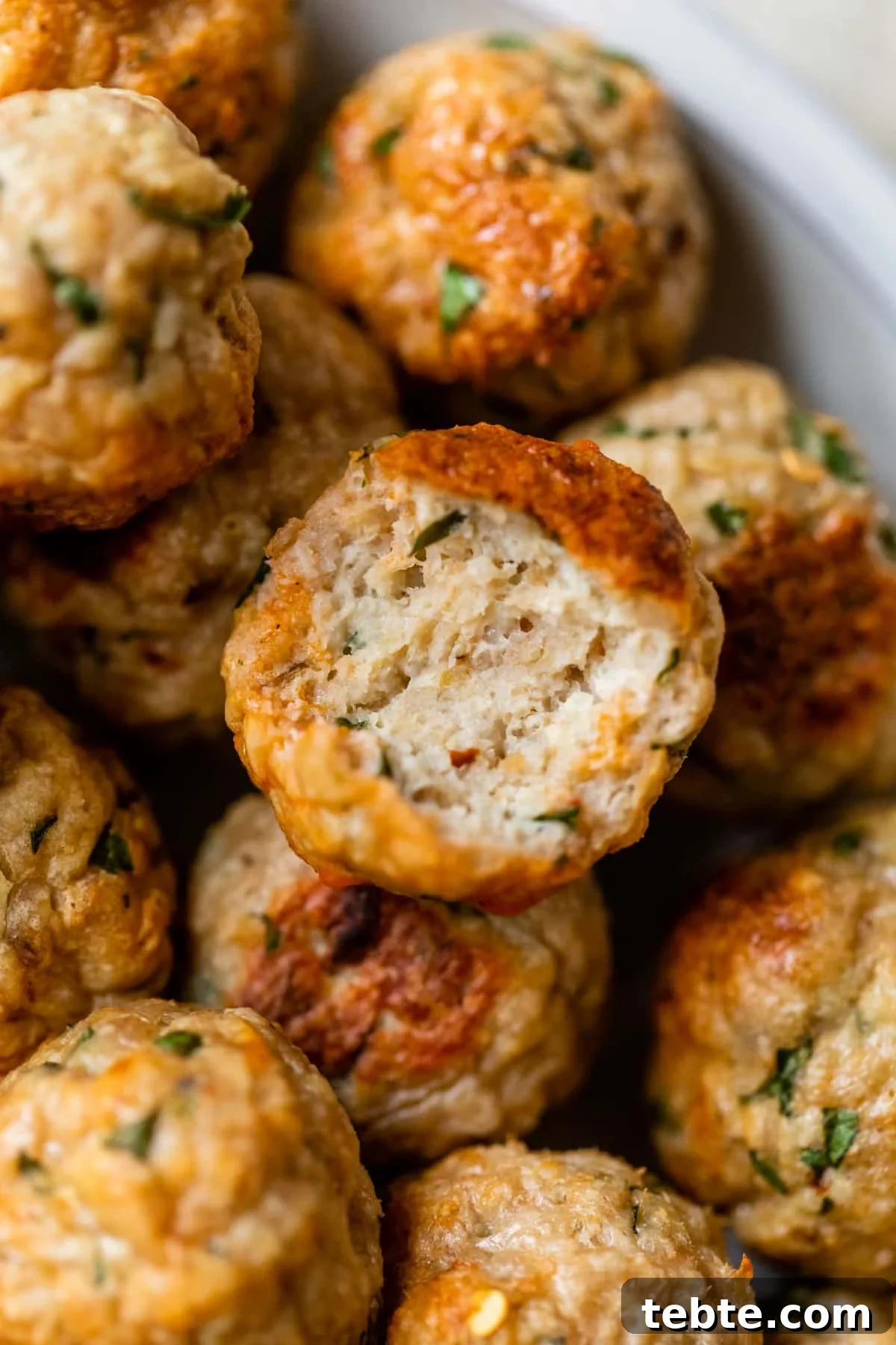 Crispy Baked Chicken Meatballs with Garlic Herb Sauce 7 meatball with a bite taken out of it