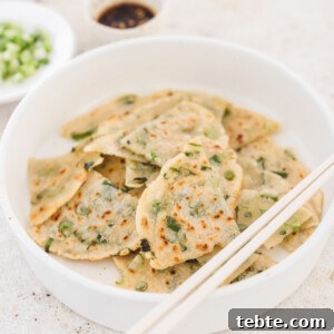 taiwanese pancakes on a white plate next to dipping sauce.