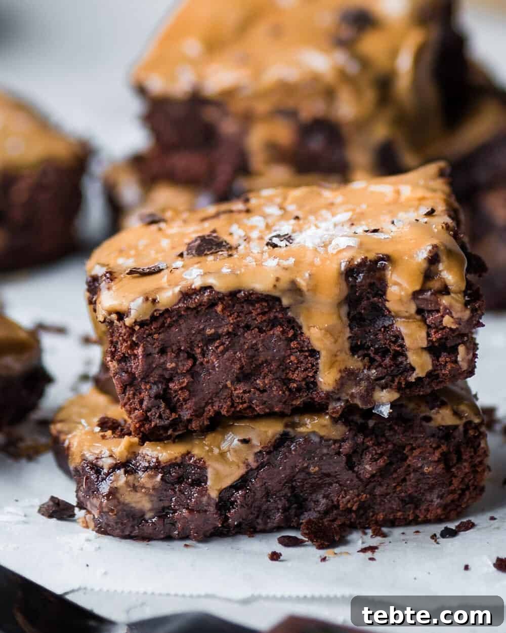 Vegan Gingerbread Brownies with Espresso Glaze Recipe 11 Two brownies stacked on a piece of parchment paper.