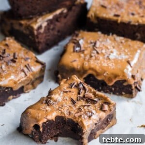 Vegan Gingerbread Brownies with Espresso Glaze Recipe 12 5 brownies on parchment paper, one with a bite taken from it.