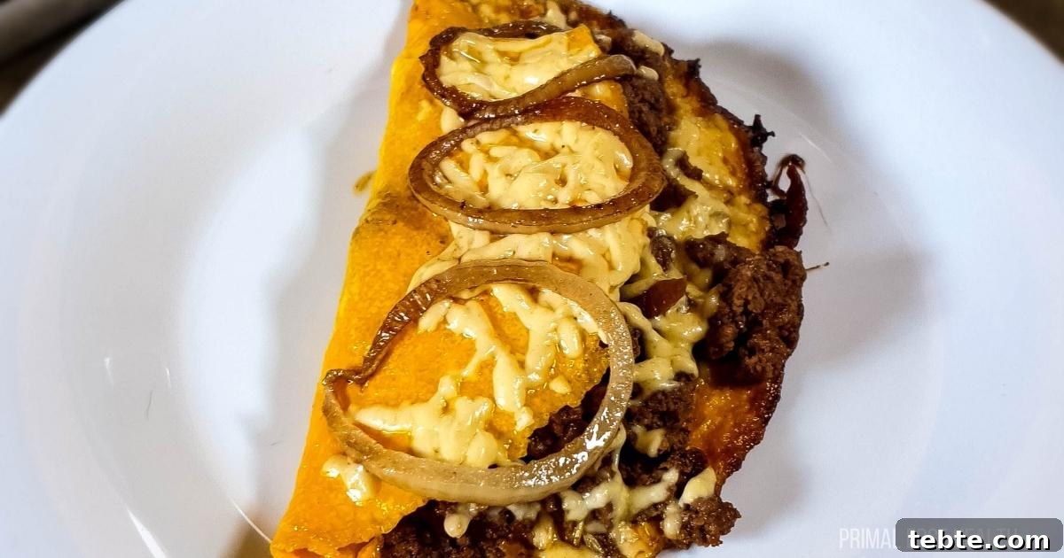 13 High-Protein Game Day Breakfasts to Fuel Your Morning 12 Cheeseburger omelette with ground beef on plate next to salt and pepper shakers.