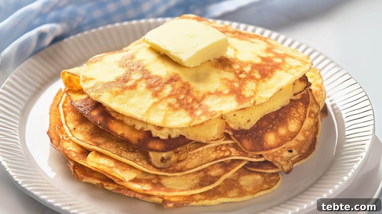 13 High-Protein Game Day Breakfasts to Fuel Your Morning 3 A stack of golden pancakes topped with a square of butter on a white plate.