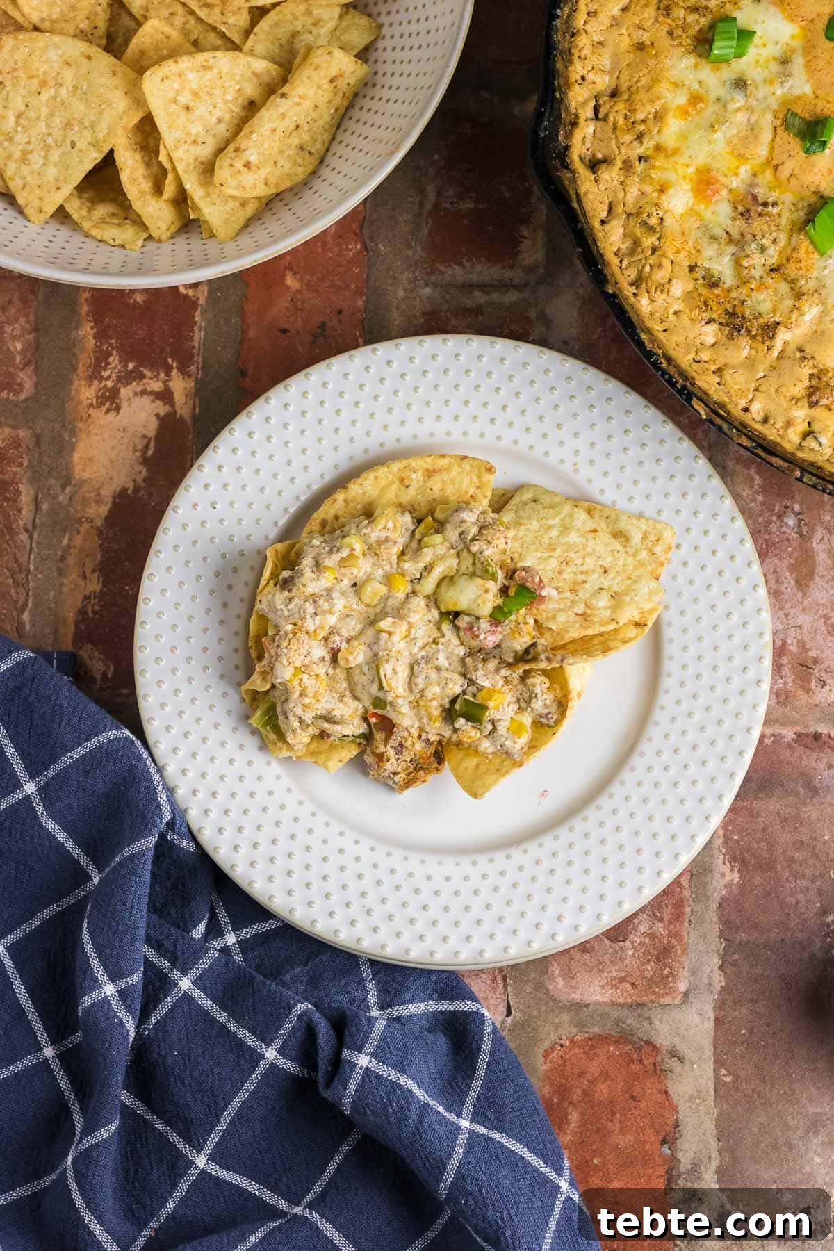 Savory Baked Cowboy Dip Recipe for Parties and Game Day 5 Cowboy dip on top of a pile of tortilla chips on a plate.