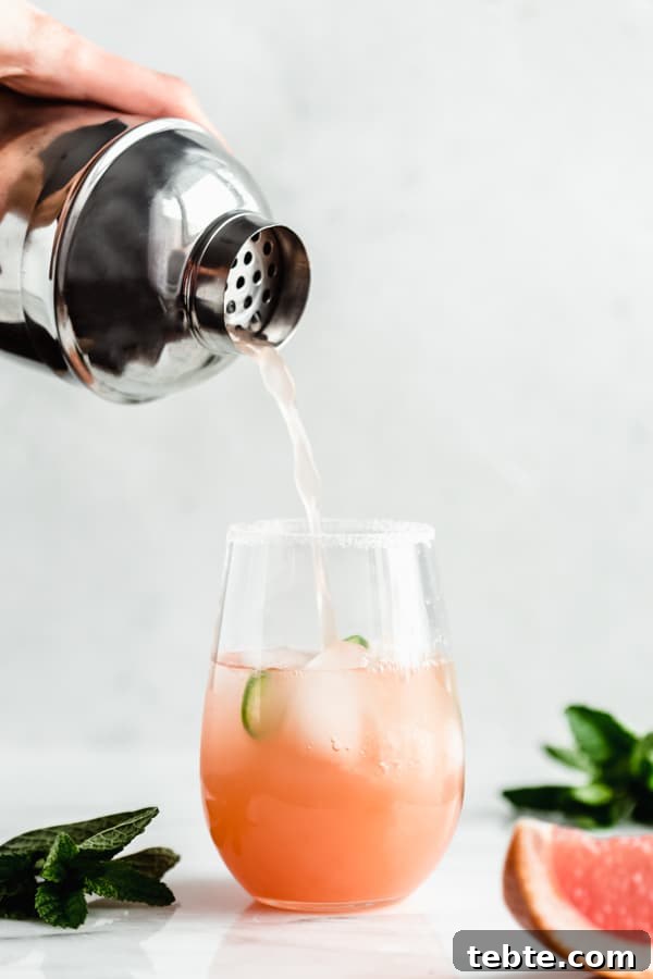 Spicy Grapefruit Margarita Recipe — Zesty Cocktail with Chili Salt Rim 3 pouring a grapefruit margarita from a drink shaker into a glass