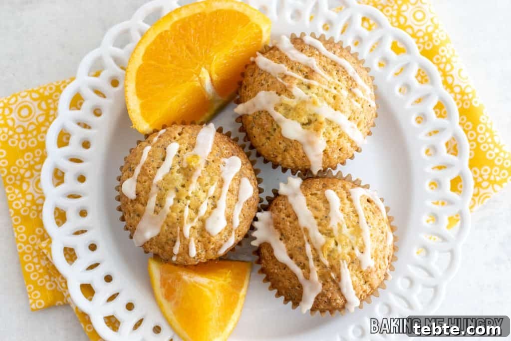 Citrus Poppy Seed Muffins with Orange Zest 3 orange poppy seed muffins on a plate with orange slices