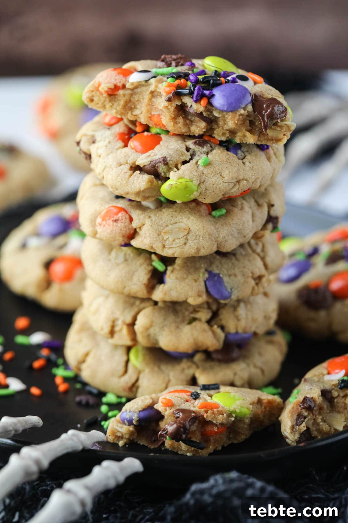 Soft Chewy Monster Cookies with Chocolate, Oats & Peanut Butter 2 monster cookies stacked on a black plate.