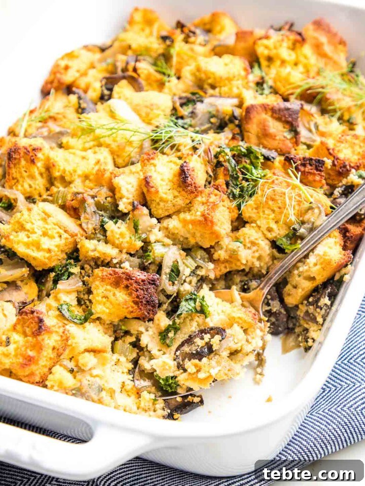 White casserole dish filled with cornbread stuffing, including mushrooms, kale, celery and fresh herbs.