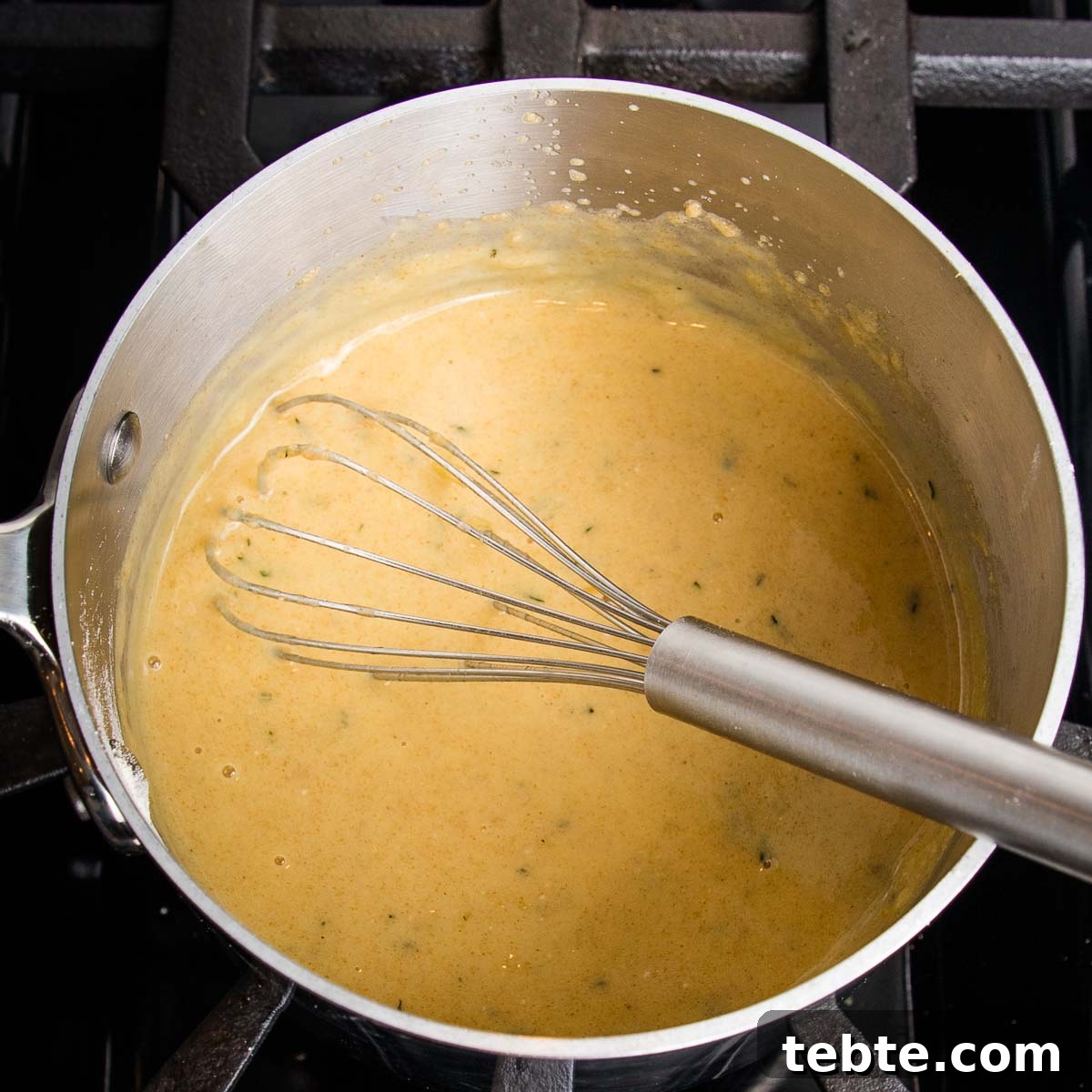 Creamy Vegan Mushroom Gravy Recipe 8 Whisking golden gravy in a small saucepan.