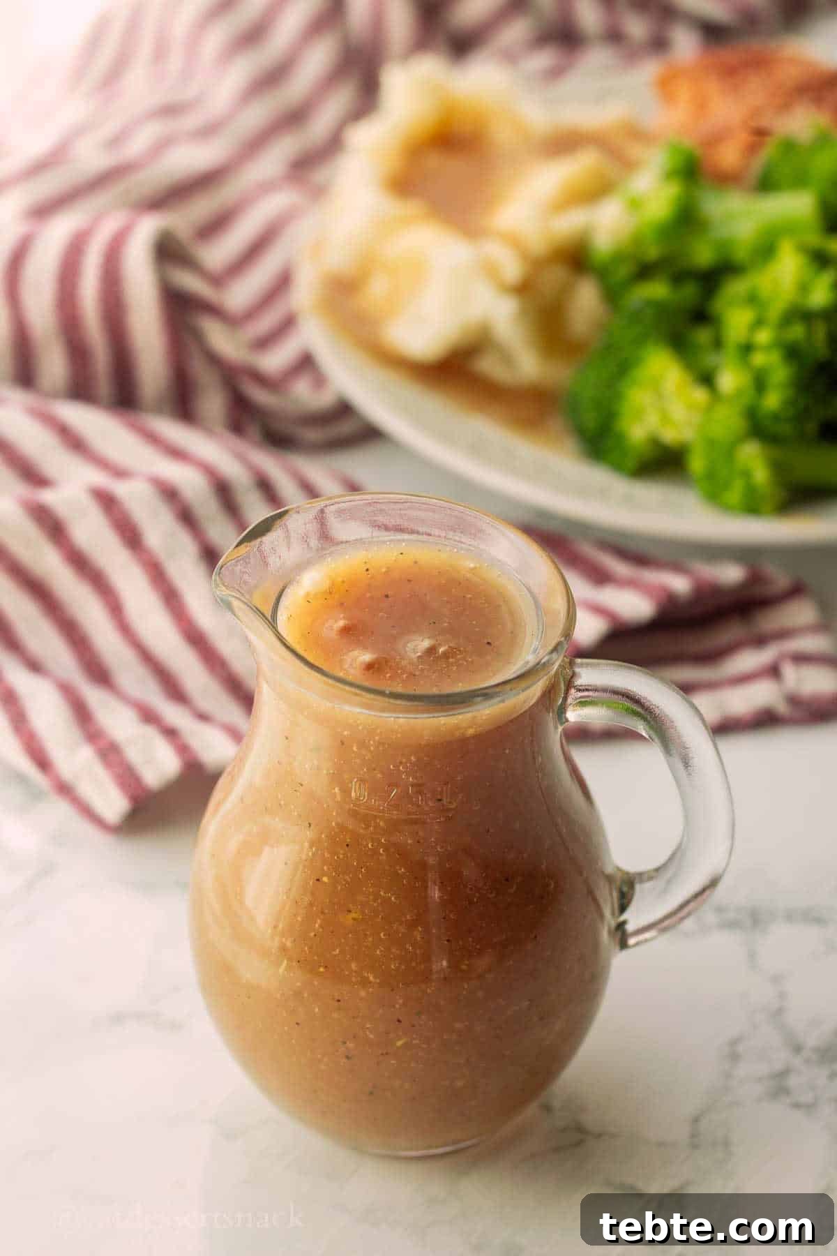 Homemade Brown Gravy Recipe for Roast and Mashed Potatoes 2 Glass pitcher of gravy on marble.