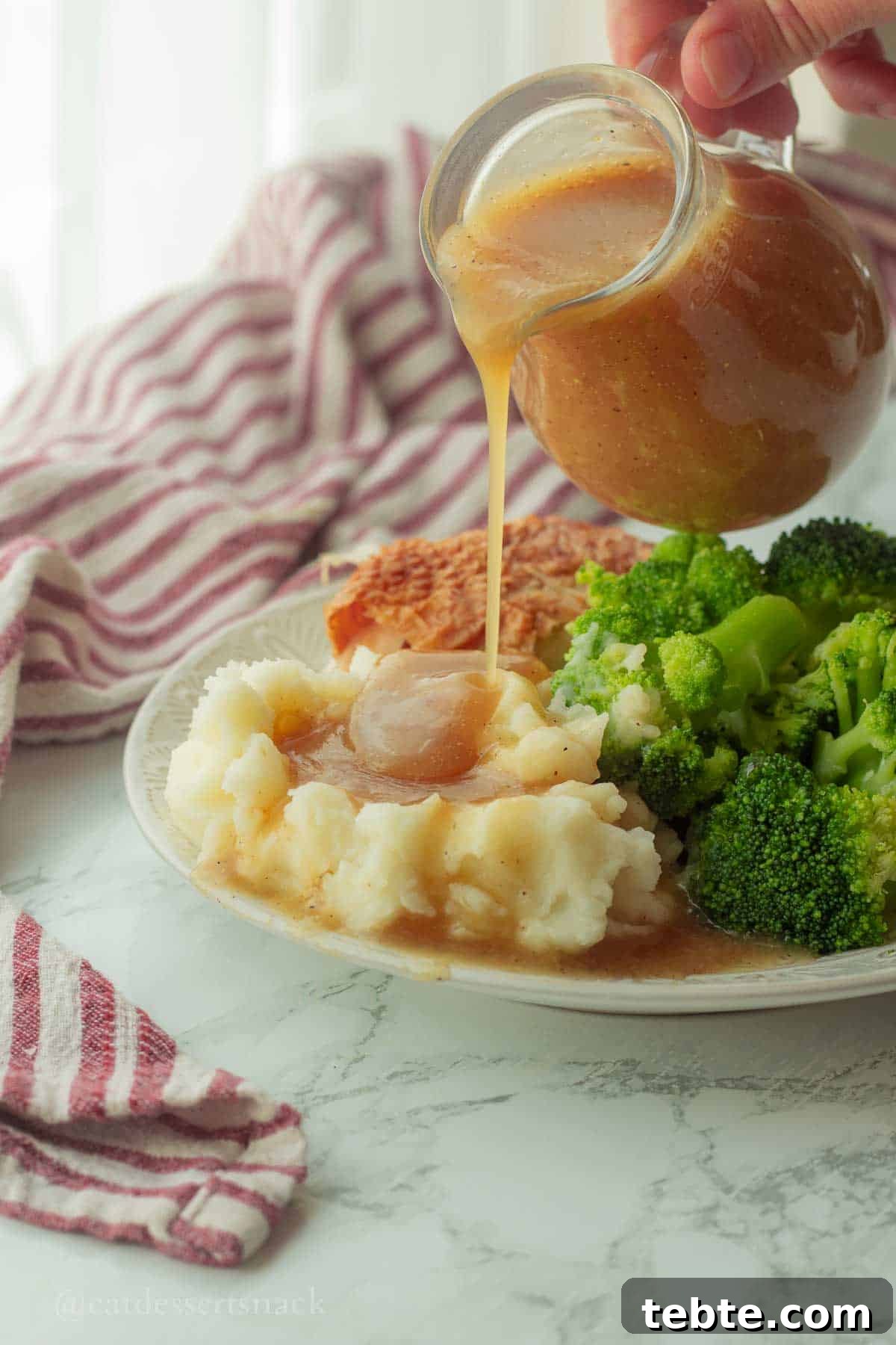 Homemade Brown Gravy Recipe for Roast and Mashed Potatoes 6 Pouring gravy onto a plate of potatoes.