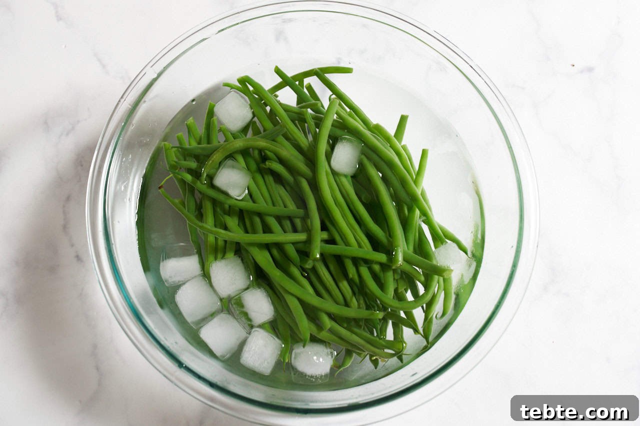 Blanched green beans in a bowl of ice water.