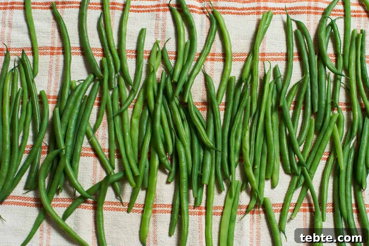 Blanched green beans (haricots verts) drying on an orange and white kitchen towel.