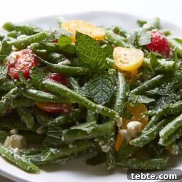 Green bean salad with feta and mint on a white plate.