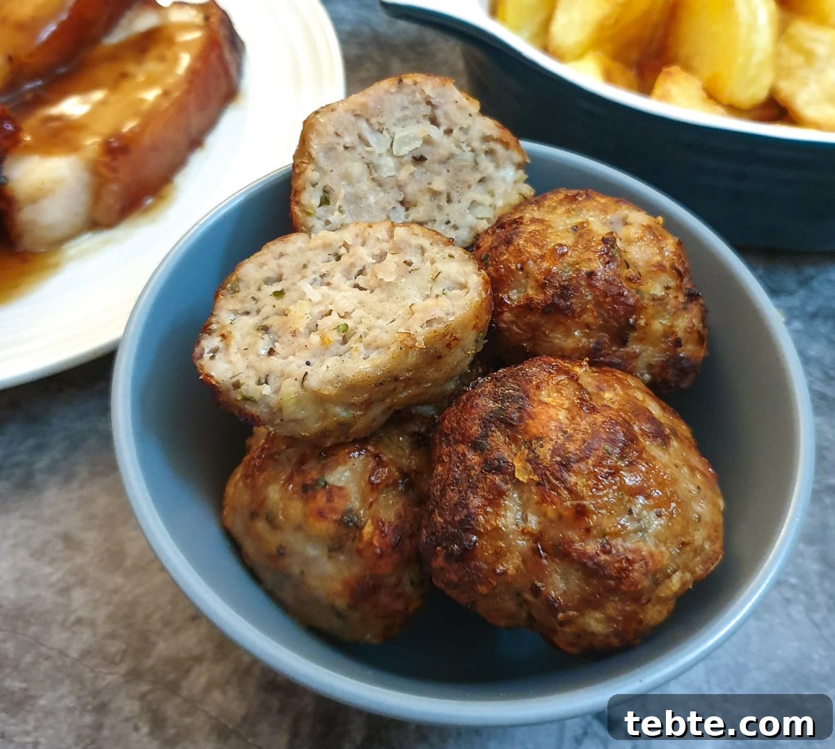 Sausage Stuffing with Sage and Onion 2 Sage and onion sausage stuffing balls in a dish with one cut in half to show the texture.