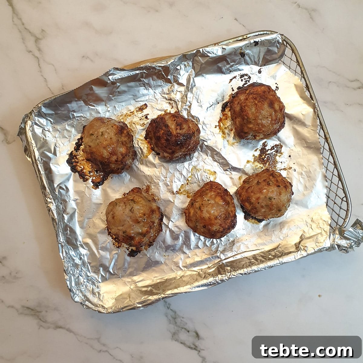 Sausage Stuffing with Sage and Onion 11 6 cooked stuffing balls on an air-fryer oven shelf.