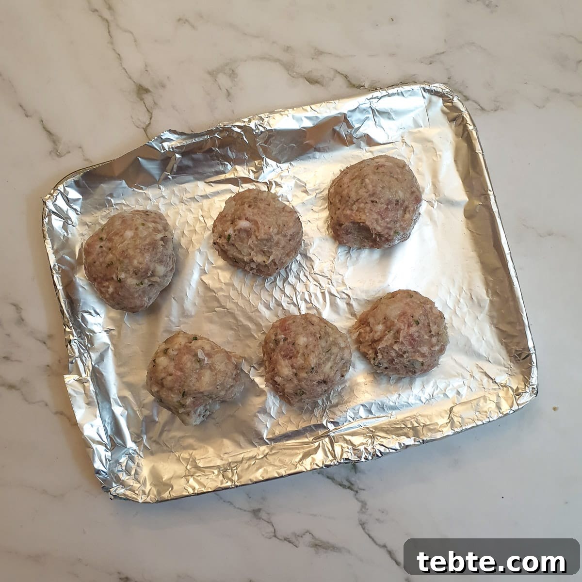 Sausage Stuffing with Sage and Onion 10 6 uncooked stuffing balls on an air-fryer oven shelf.