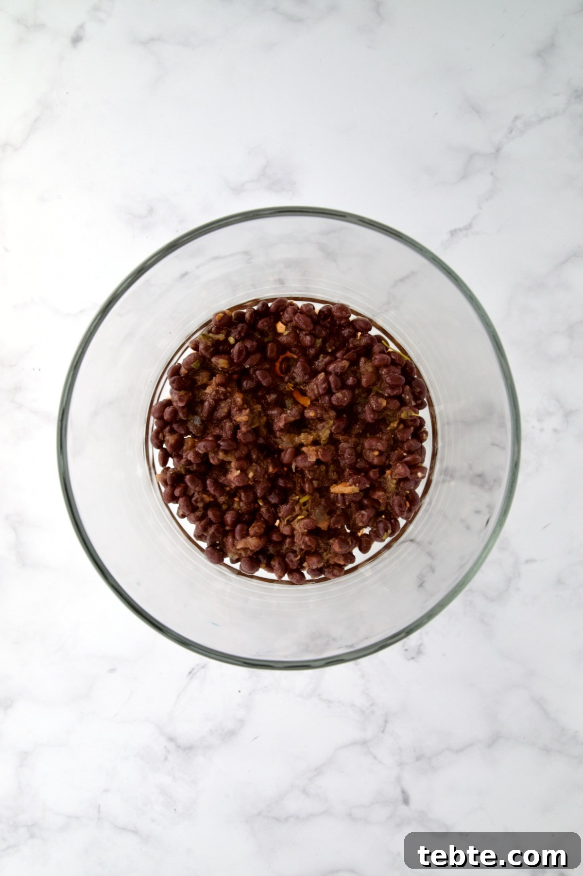 Layered Southwestern Salad with Corn, Black Beans, and Avocado 6 Black beans combined with salsa in glass footed serving bowl.