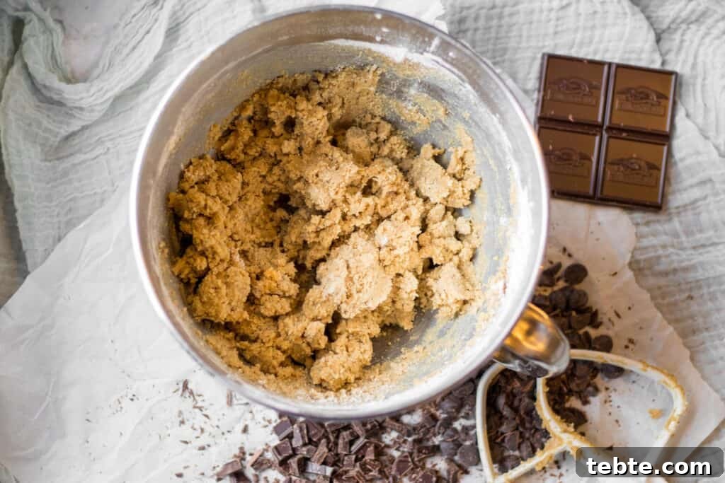 Coffee Chocolate Chunk Shortbread Cookies 7 mixing bowl with coffee chocolate chunk shortbread dough in it, with paddle mixer and chocolate chips on the side