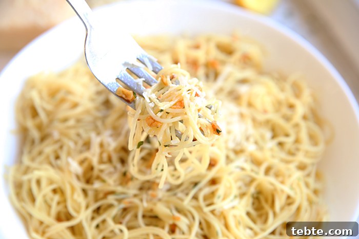 Fancy-Looking Christmas Eve Dinner Ideas for Busy Families 12 a fork getting a bite of angel hair noodles with sauteed garlic and parmesan out of a large bowl of the recipe.