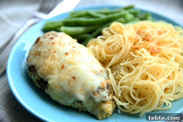 Fancy-Looking Christmas Eve Dinner Ideas for Busy Families 5 a juicy chicken breast with seasoning and cheese next to noodles and green beans