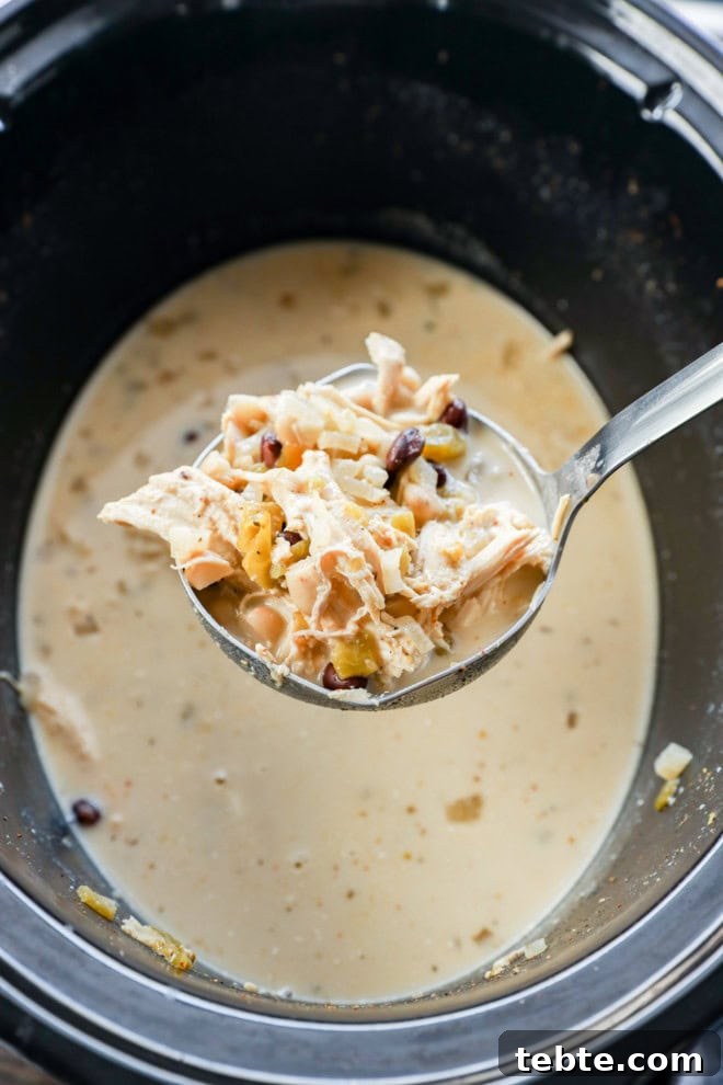 Creamy White Chicken Chili in the Slow Cooker 7 Scooping out soup from a crockpot with a ladle