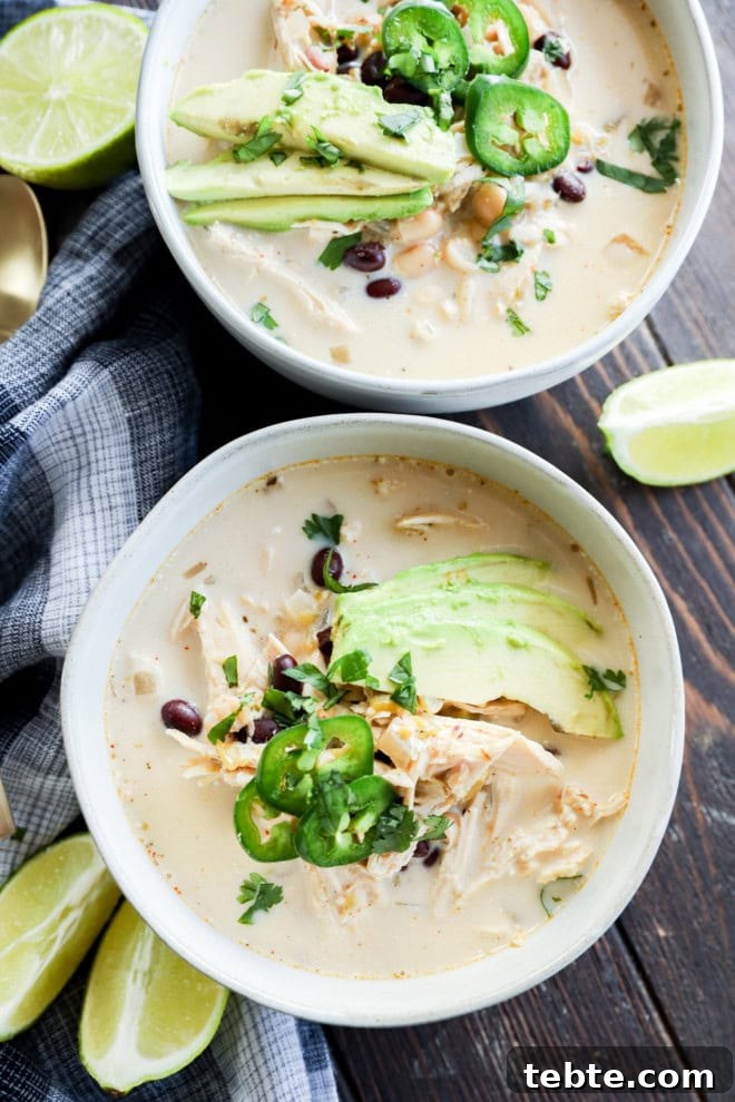 Creamy White Chicken Chili in the Slow Cooker 8 two bowls of soup with lots of toppings and lime wedges on the side