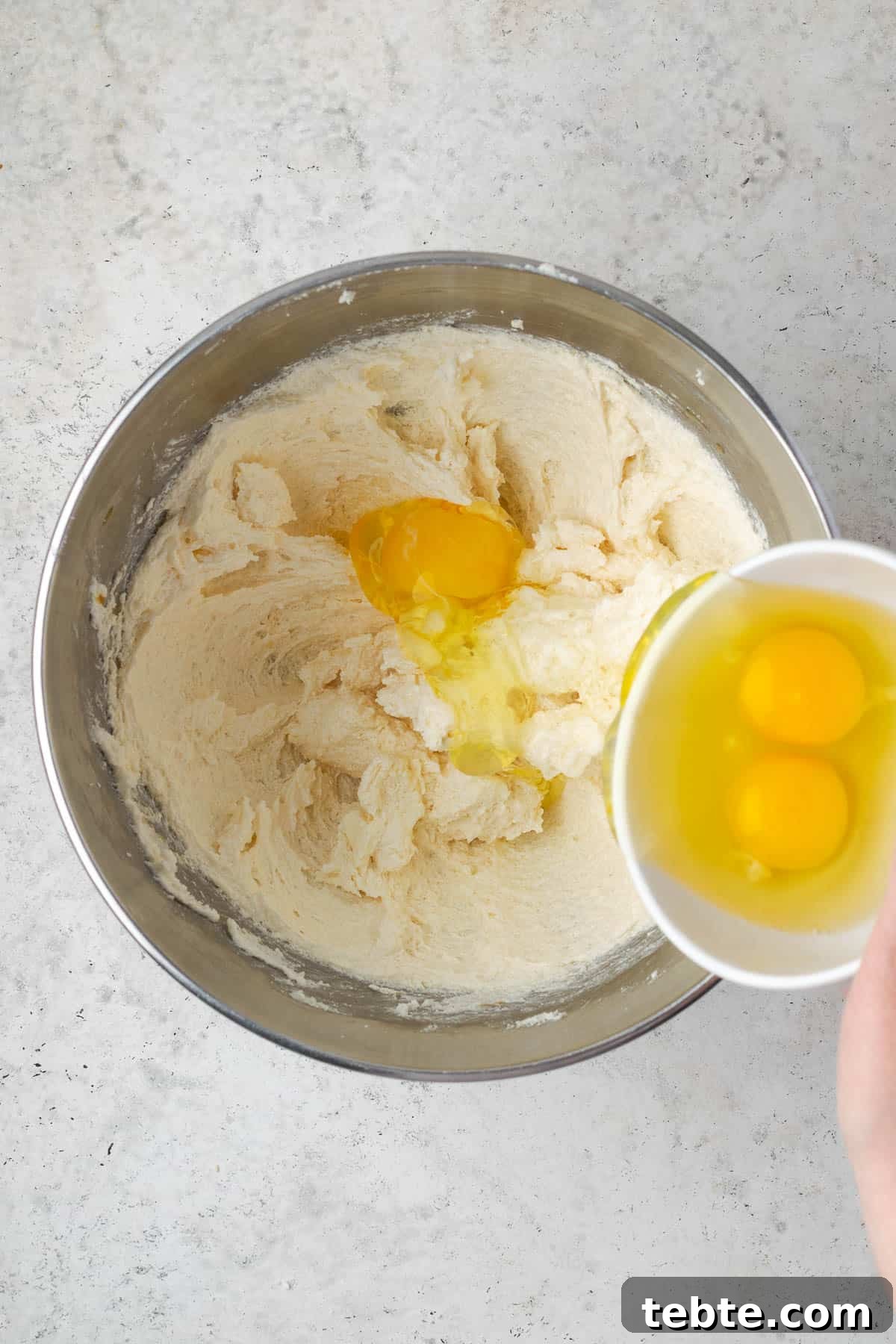 Classic Cranberry Orange Pound Cake Recipe 7 Eggs being added one at a time to the partially mixed cake batter.