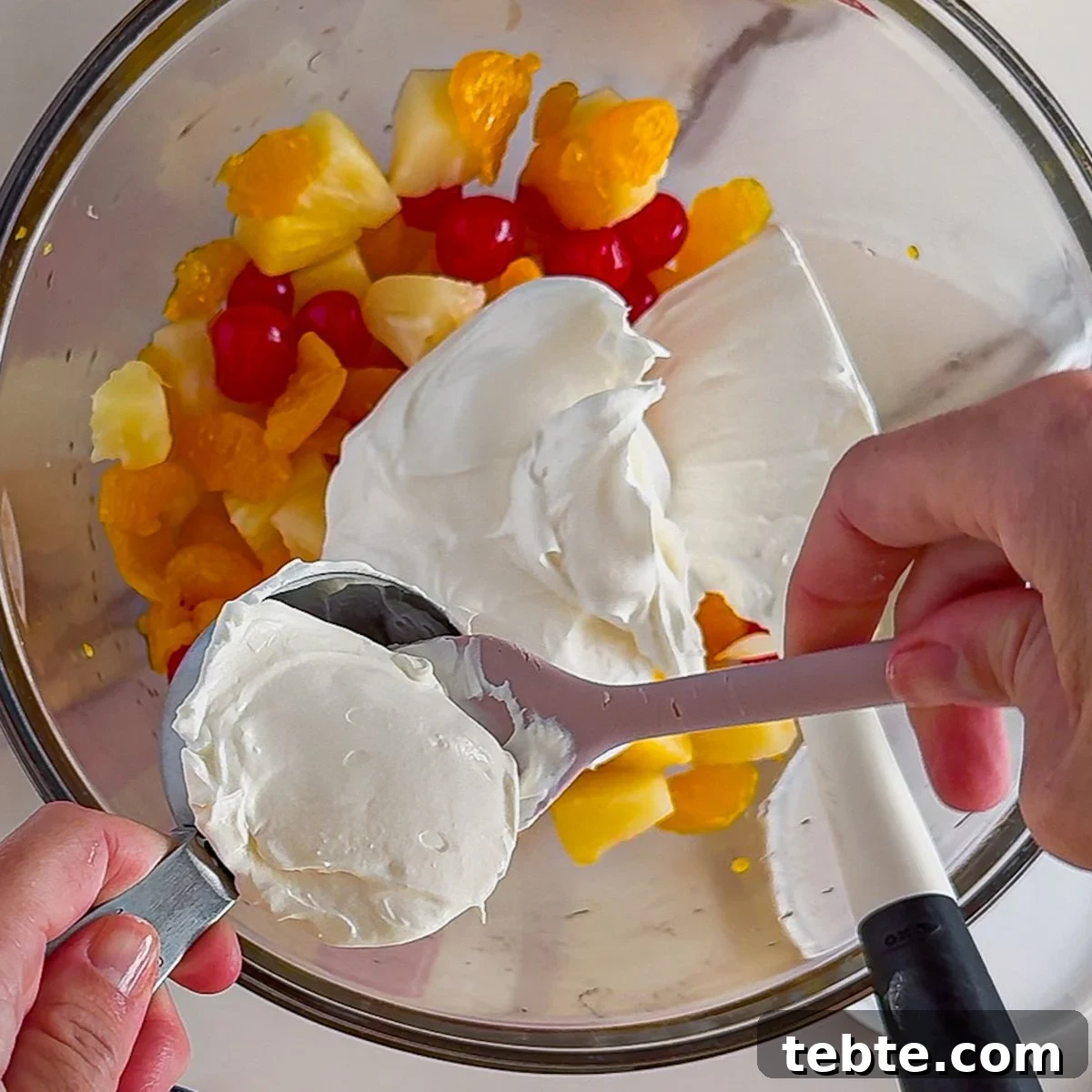 Classic Ambrosia Salad Recipe with Citrus and Coconut 5 Mixing in the cool whip into the ambrosia salad.