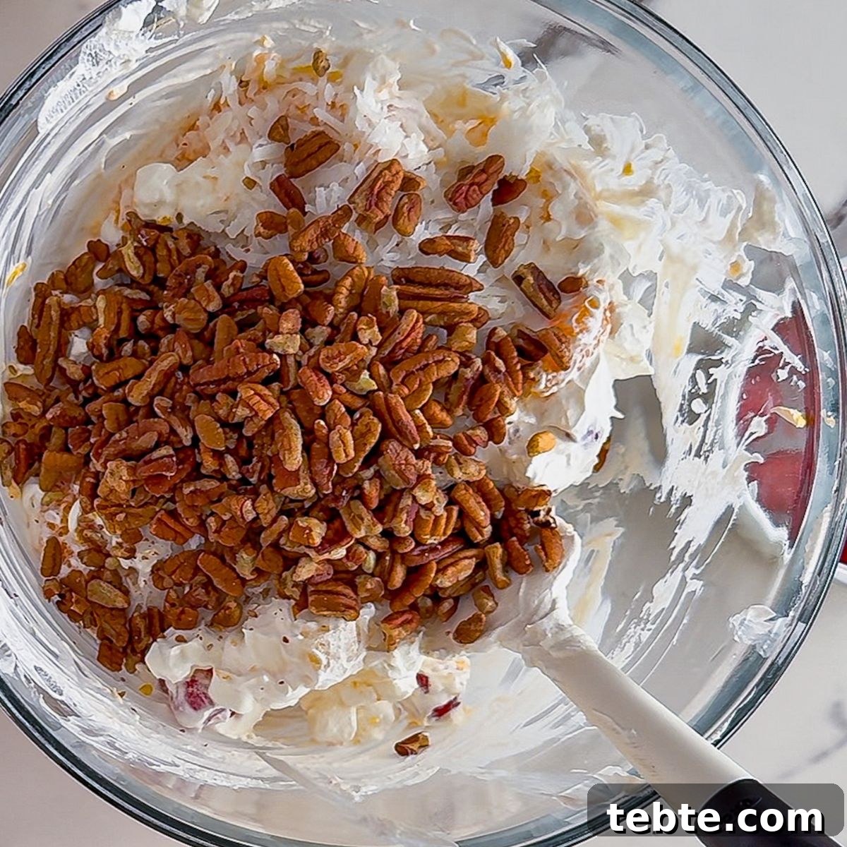 Classic Ambrosia Salad Recipe with Citrus and Coconut 7 Mixing ambrosia salad.