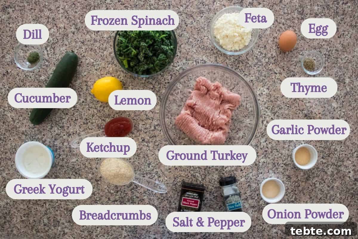 Savory Greek Meatloaf with Spinach and Feta 3 A top view of various labeled ingredients on a countertop, including ground turkey in a bowl, frozen spinach, feta, egg, cucumber, lemon, dill, thyme, ketchup, garlic powder, Greek yogurt, breadcrumbs, salt, pepper, and onion powder.