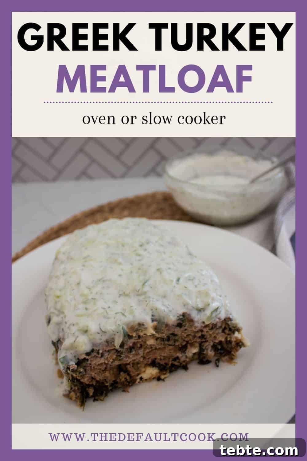 Savory Greek Meatloaf with Spinach and Feta 7 A slice of Greek turkey meatloaf topped with a creamy white sauce sits on a white plate. In the background, there’s a bowl of the same sauce.