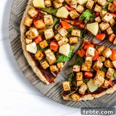 Vegan Calzones with Homemade Vegan Pizza Dough 16 completed vegan bbq pizza sliced into quarters on a textured circular board against a white background