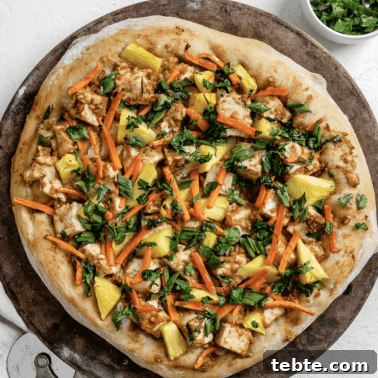 Vegan Calzones with Homemade Vegan Pizza Dough 18 completed shot of thai pizza post being baked on brown and white surface with a slice cut out