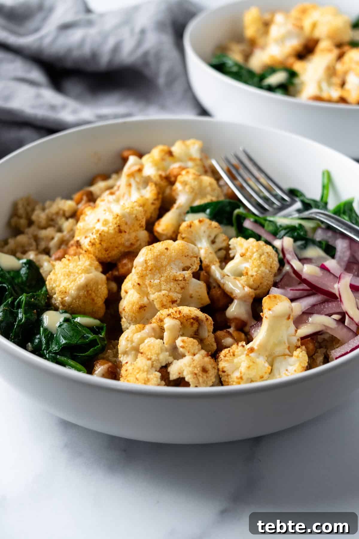 Crispy Roasted Cauliflower Bowl Recipes 2 Roasted Cauliflower Bowls on a marble countertop.